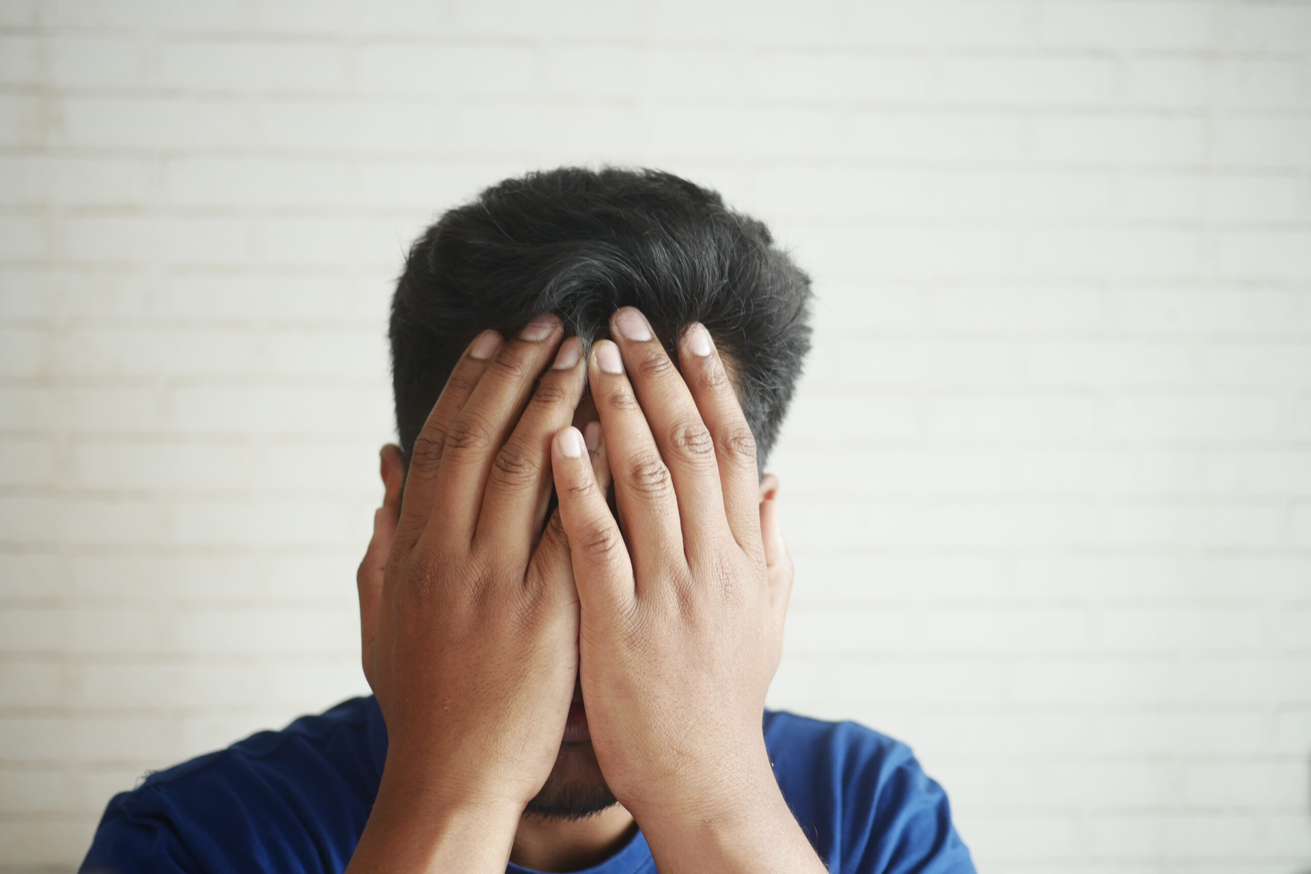 Close up of sad man covering face with hand. Close up of sad man covering face with hand