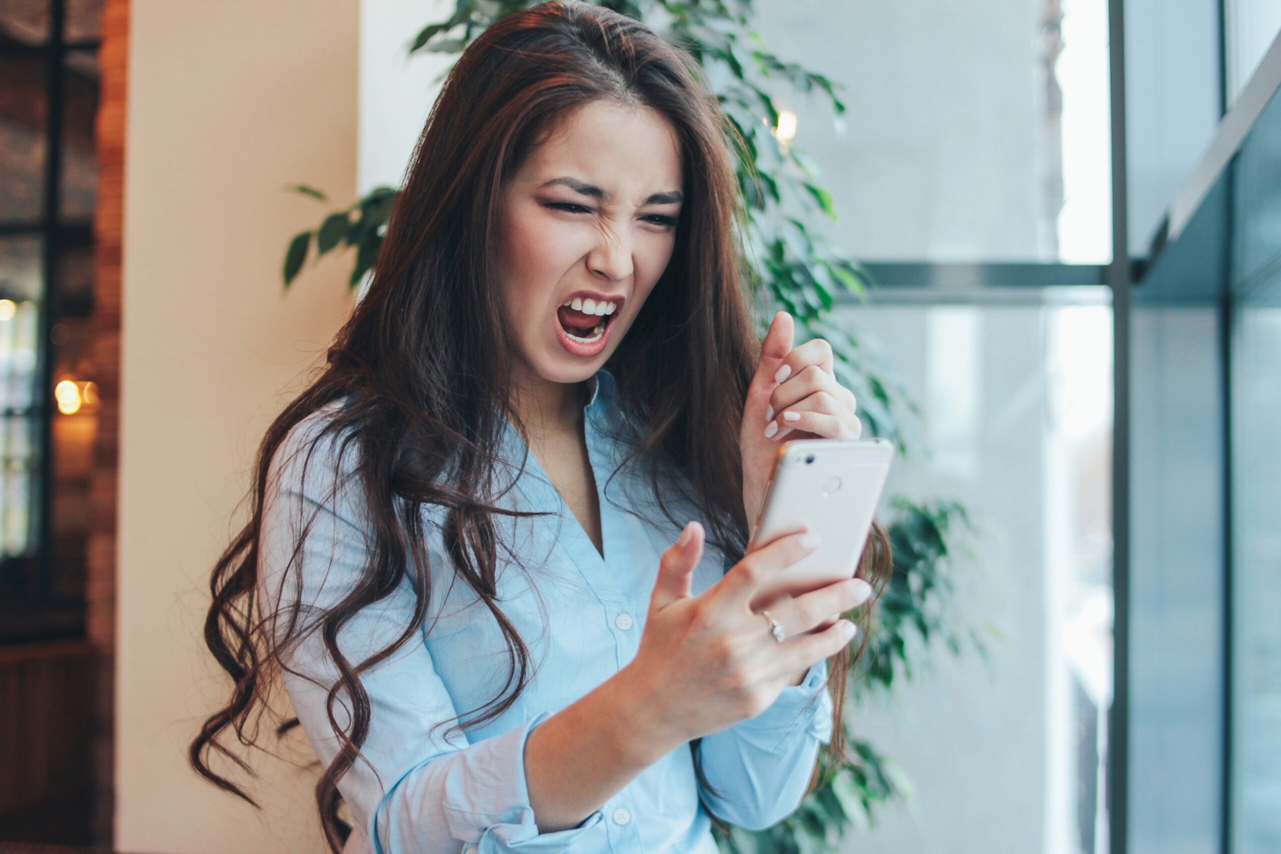 Beautiful charming brunette angry asian girl screaming on phone in cafe Beautiful charming brunette angry asian girl screaming on phone in cafe