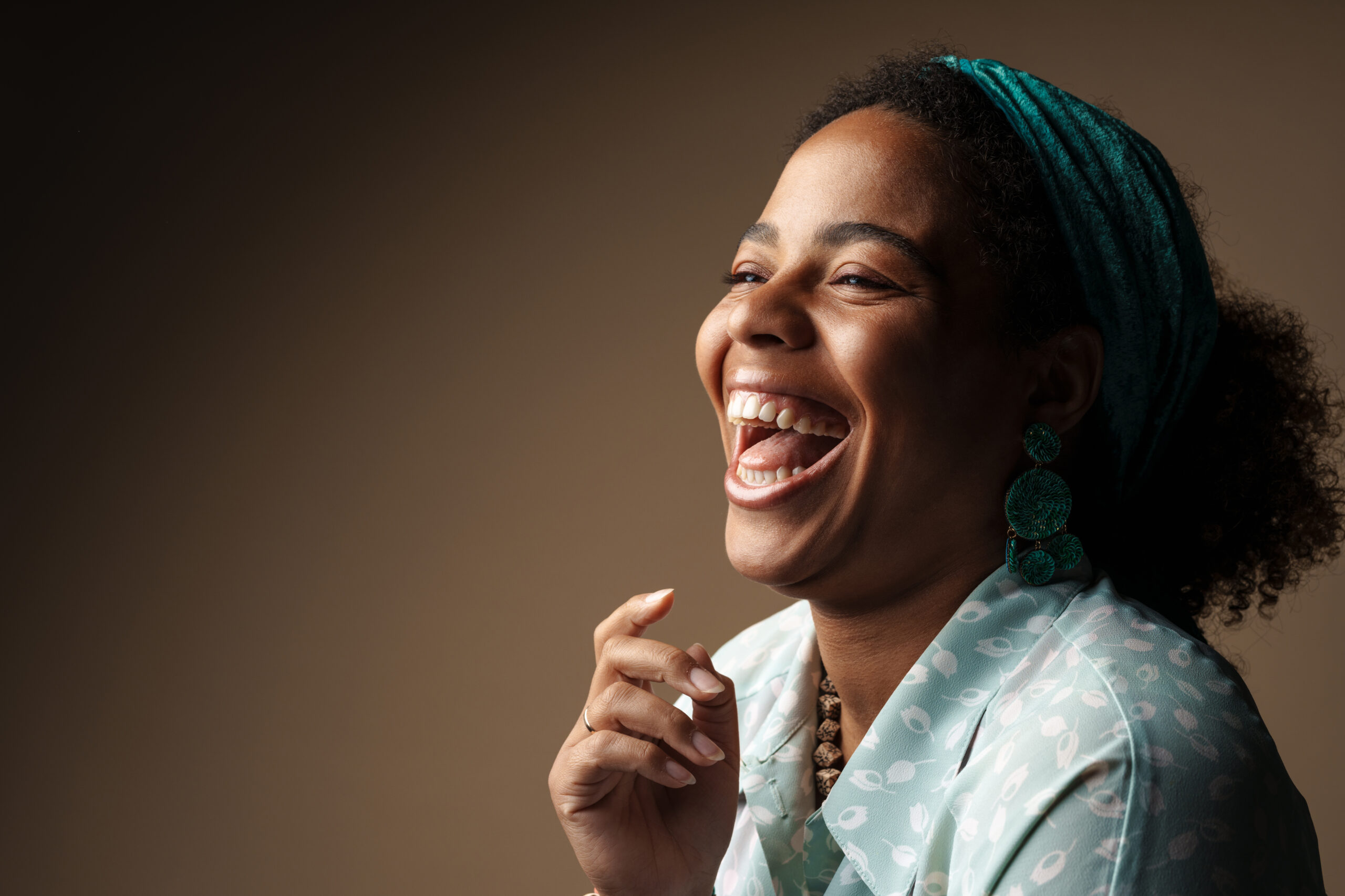 Young black woman in headband laughing and looking aside Young black woman in headband laughing and looking aside isolated over grey background